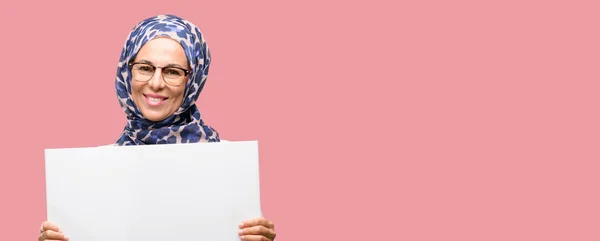 空白の広告バナー 提供または発表 大きな紙の看板の良いポスターを保持ヒジャーブを着て中年イスラム アラブ女性 — ストック写真