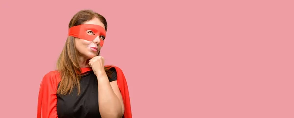 中年超级英雄妇女身穿红面具和海角思考和寻找表达怀疑和疑惑 — 图库照片