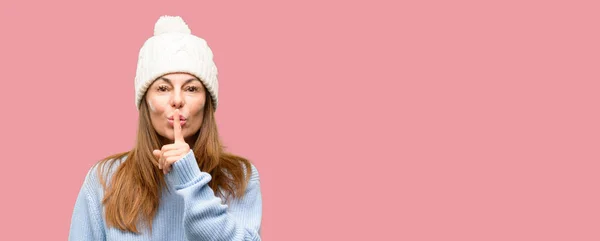 中間の年齢の女性の唇に人差し指をウール冬帽をかぶって 静かにするように求めます 沈黙と秘密の概念 — ストック写真