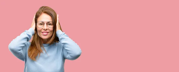 中年女子身穿羊毛毛衣和清凉眼镜遮盖耳朵 不理会恼人的噪音 堵塞耳朵以避免听觉声音 嘈杂的音乐是个问题 — 图库照片