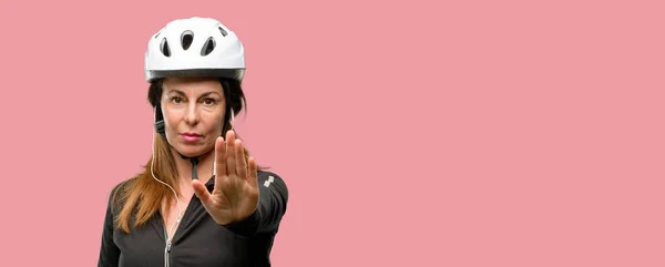 中年骑自行车的女人用耳机烦坏态度做停止手势 表示安全 防守或限制 也许推 — 图库照片