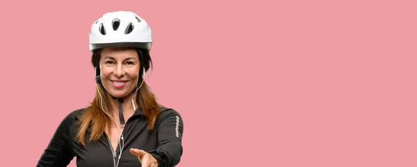 イヤホンを使用して中年サイクリスト女性握手ポーズを歓迎する 信頼と成功のコンセプトを表現する 挨拶の手を保持します — ストック写真