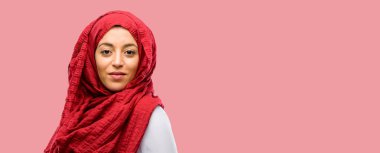 Kameraya bakarak büyük bir doğal gülümseme ile kendinden emin ve mutlu hijab giyen genç Arap kadın