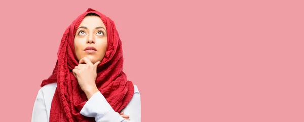 年轻的阿拉伯妇女戴头巾思考和寻找表达怀疑和疑惑 — 图库照片