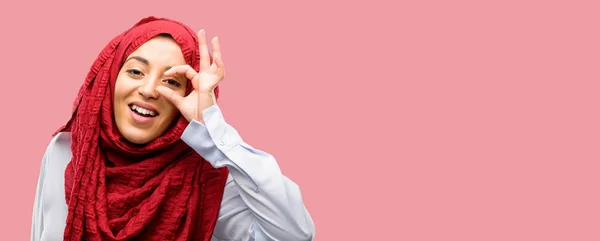 年轻的阿拉伯妇女戴着头巾看着相机通过她的手指在 模仿望远镜 美丽的眼睛和微笑 — 图库照片
