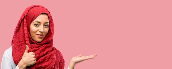 Młoda Kobieta Arabska Noszenie Hidżabu Kciuk Trzyma Coś Ręku Pusty — Zdjęcie stockowe