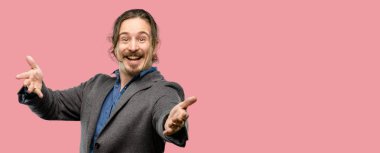 Yakışıklı genç adam kendinden emin ve mutlu bir büyük doğal gülümseme hoş geldiniz hareketi ile