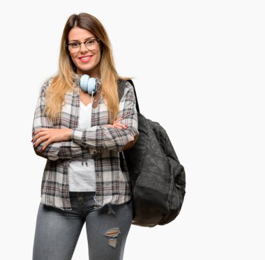 Genç öğrenci kadın kendinden emin ve mutlu bir büyük doğal gülümseme gülmek ile çapraz kollu sırt çantası ve kulaklık ile
