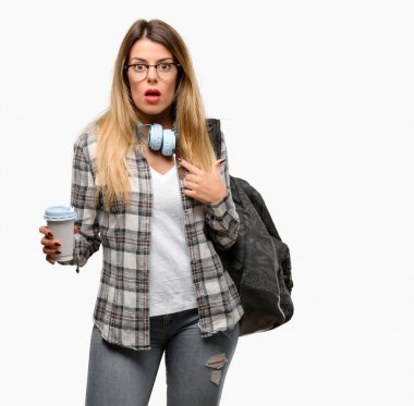 Parmak ile işaret genç öğrenci kadın sırt çantası mutlu ve ifade wow jest, tezahürat ve kulaklık ile