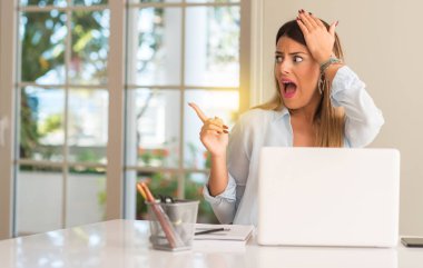 Öğrenci kadın masada evde laptop ile uzak yan parmak ile işaret