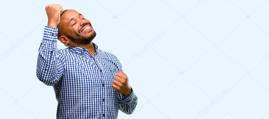 African american man with beard happy and excited expressing winning gesture. Successful and celebrating victory, triumphant isolated over blue background