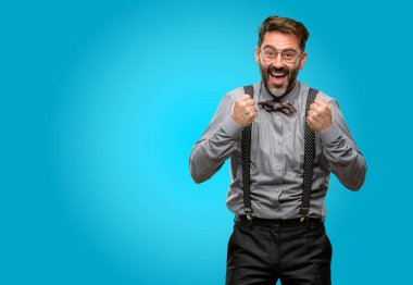 Orta yaş adam, sakal ve papyon mutlu ve heyecanlı kazanan jest ifade. Başarılı ve zafer, zafer kutluyor