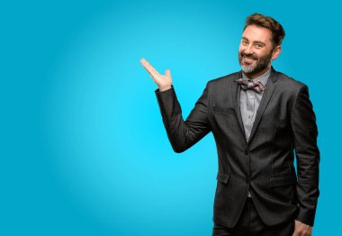 Orta yaş adam, sakal ve papyon bir şey boş elinde tutan