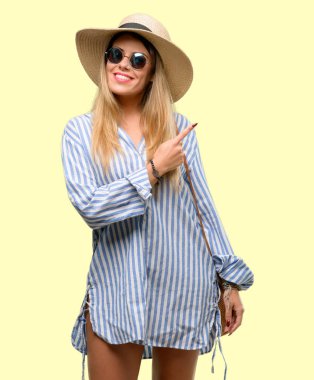 Güneş gözlüğü ve uzak yan parmak ile işaret yaz şapka giyen genç kadın