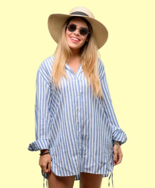 Güneş gözlüğü ve kendinden emin ve mutlu bir büyük doğal gülümseme gülmek ile yaz şapka giyen genç kadın