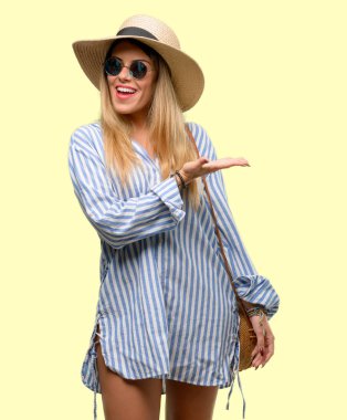 Güneş gözlüğü ve bir şey boş elinde tutan yaz şapka giyen genç kadın