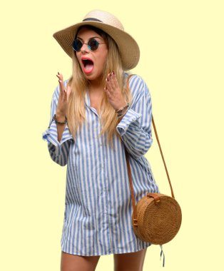 Güneş gözlüğü ve stresli yaz şapka giyen genç kadın kafasına, panik içinde dehşete ellerini tutmak, bağırarak