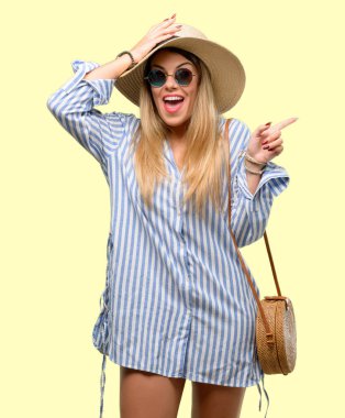 Güneş gözlüğü ve uzak yan parmak ile işaret yaz şapka giyen genç kadın