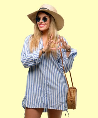 Eller genç kadın güneş gözlüğü ve yaz şapka ile sevgi göstermekten mutlu kalp şekli sağlıklı ifade ve evlilik sembolü