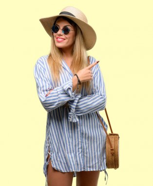 Güneş gözlüğü ve uzak yan parmak ile işaret yaz şapka giyen genç kadın