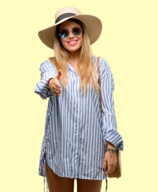 Güneş gözlüğü ve yaz şapka giyen genç kadın el sıkışma poz karşılama, güven ve başarı kavramı ifade, tebrik ellerini tutar