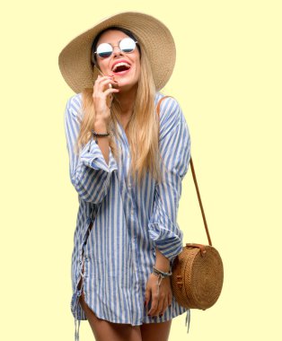 Güneş gözlüğü ve yaz şapka mutlu bir smartphone cep telefonuyla konuşurken giyen genç kadın