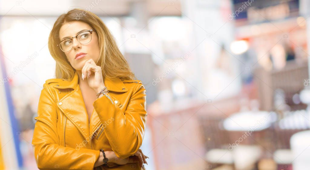 Beautiful young woman thinking and looking up expressing doubt and wonder at restaurant