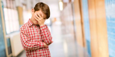 Baş, yorgun ve sinirli stresli tutmak ellerinde okul koridor az yakışıklı yürümeye başlayan çocuk yeşil gözleri