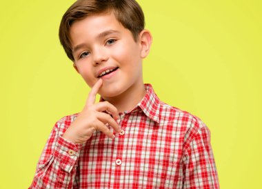 Kendinden emin ve mutlu sarı arka plan üzerinde gülüyor büyük bir doğal gülümseme ile yeşil gözlü yakışıklı yürümeye başlayan çocuk