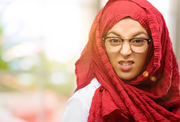 Kızgın ve stresli hijab giyen genç Arap kadın tedirgin ve rahatsız, tatminsizlik, yüzüne frowns öfke ifade