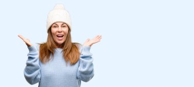 Orta yaş kadın giyiyor yün kış kap mutlu ve ifade wow tezahürat jest izole mavi arka plan