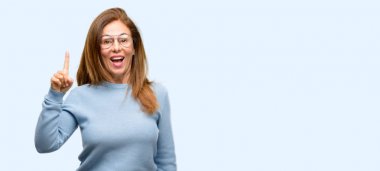 Yün kazak ve serin gözlük uzak yan parmak ile işaret orta yaş kadın mavi arka plan izole