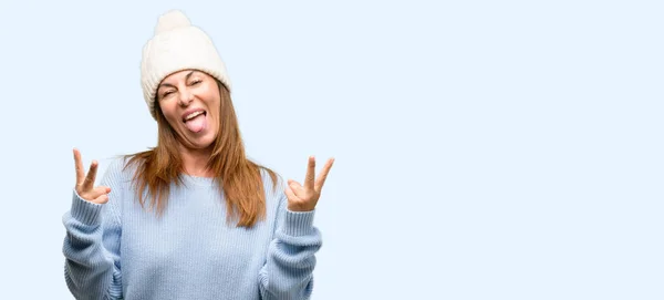 トングを示し指分離青い背景の署名の勝利を作るカメラ目線ウール防寒帽を身に着けている中年女性 — ストック写真