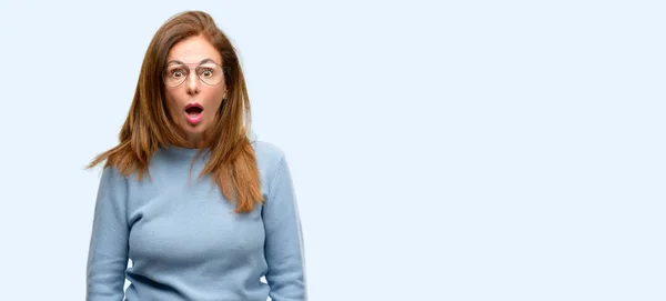 中間の年齢の女性着てウールのセーターとクールな眼鏡ショックで 怖がってパニックを表現して分離の青い背景の恐怖 — ストック写真