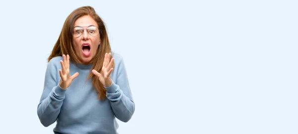中年の女性のパニックで恐怖の頭の上身に着けているウールのセーターと眼鏡クール ストレス維持手分離の青い背景を叫んで — ストック写真