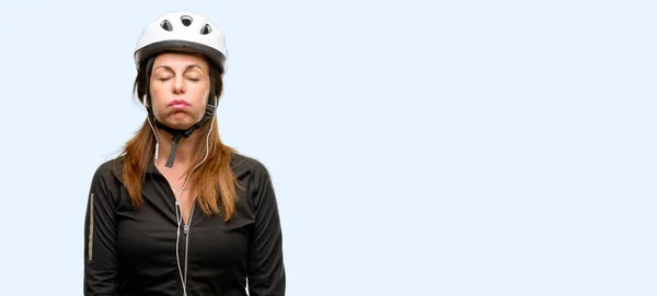 中年サイクリスト女性眠そうな表情 酷使され 疲れでイヤホンを使用して分離された青色の背景 — ストック写真