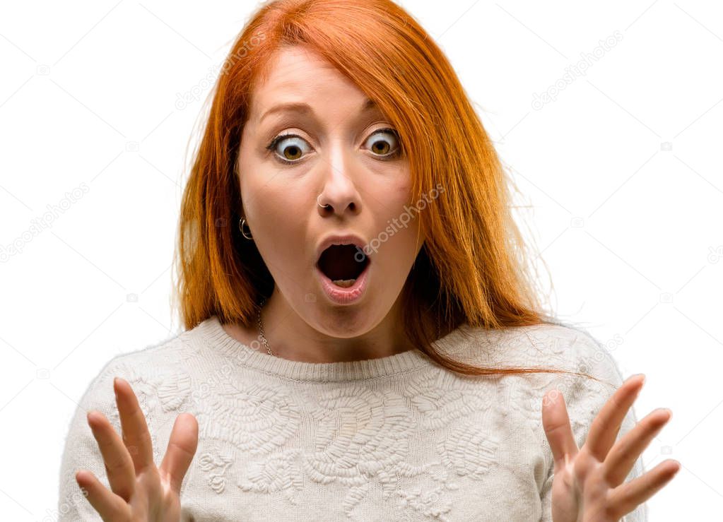 Beautiful young redhead woman stressful keeping hands on head, terrified in panic, shouting isolated over white background