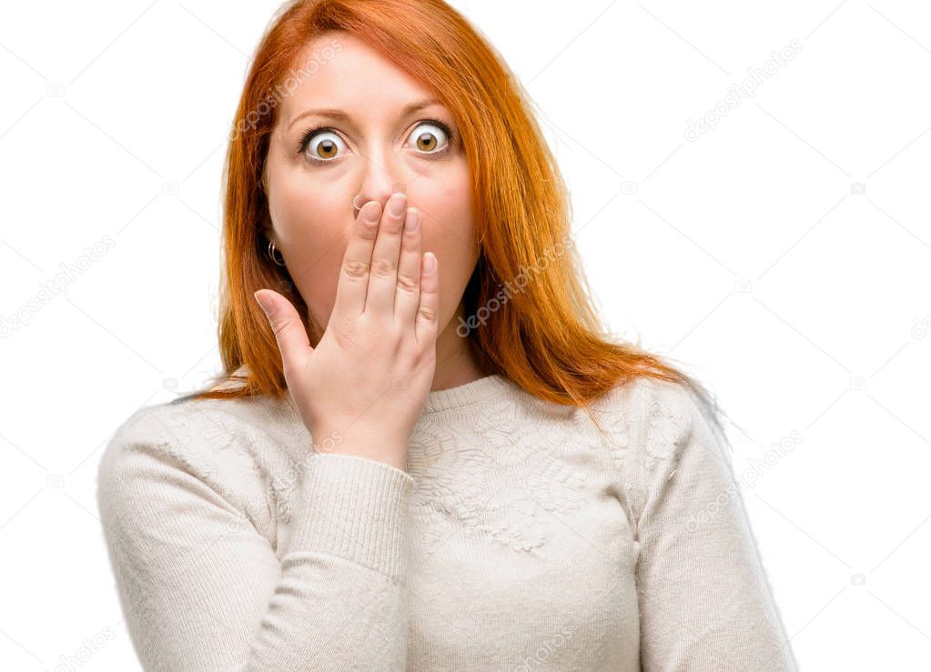 Beautiful young redhead woman covers mouth in shock, looks shy, expressing silence and mistake concepts, scared isolated over white background