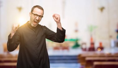 Rahip din adamı mutlu ve heyecanlı büyük başarı, güç, enerji ve olumlu duygular ifade zaferini kutluyor. Yeni iş neşeli kilisede kutluyor