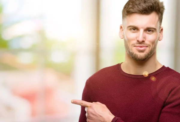 Handsome young man pointing away side with finger