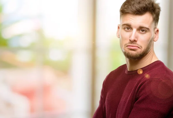 Handsome young man with sad and upset expression, unhappy