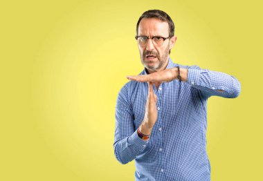 Handsome middle age man serious making a time out gesture with hands clipart