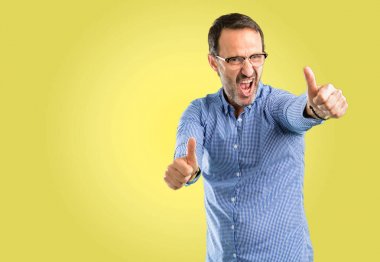 Yakışıklı orta yaş erkek stand mutlu ve iyi jest ifade büyük bir gülümseme ile onaylama yukarı başparmak ile pozitif