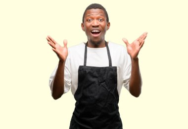 Önlük mutlu ve tezahürat ifade wow jest giyen Afrika adam dükkanı sahibi