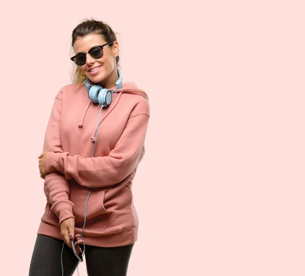 Young sport woman with headphones and sunglasses confident and happy with a big natural smile laughing