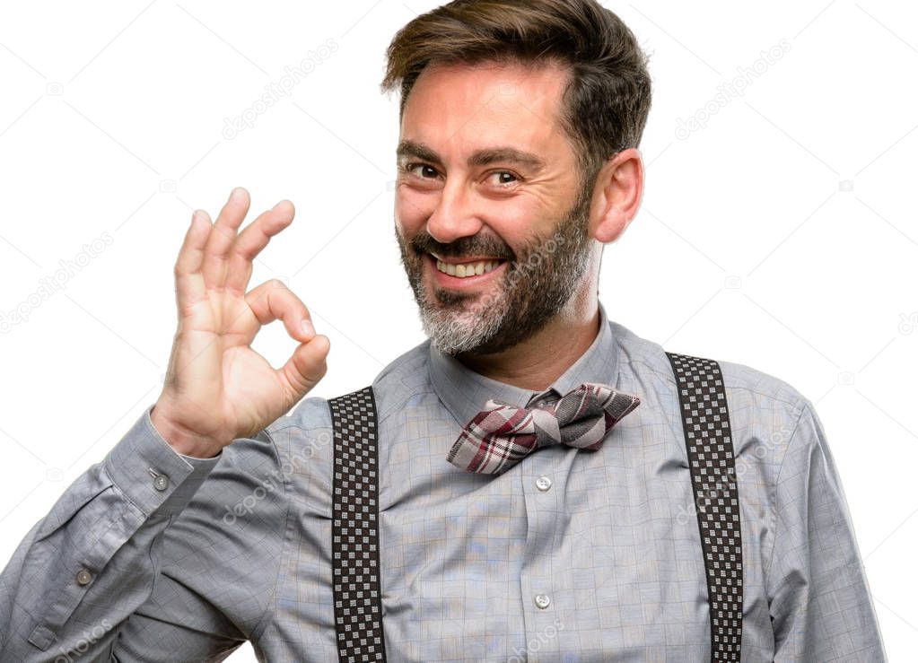 Middle age man, with beard and bow tie doing ok sign with hand, approve gesture isolated over white background