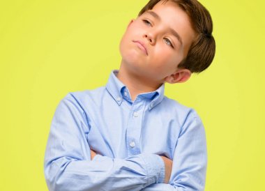 Kendinden emin ve mutlu bir büyük doğal ile çapraz kollu yeşil gözlü yakışıklı yürümeye başlayan çocuk gülümseme sarı arka plan üzerinde gülüyor