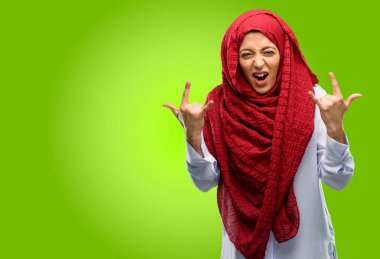 Rock simge elle yapma, bağırarak ve kutlama hijab giyen genç Arap kadın