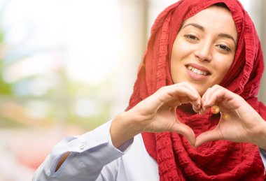 Eller ile sevgi göstermekten mutlu hijab giyen genç Arap kadın kalp şekli sağlıklı ifade ve evlilik sembolü