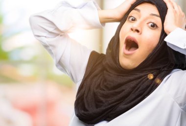 Genç Arap kadın giyiyor hijab stresli tutmak ellerinde kafa, panik, korku içinde bağırarak